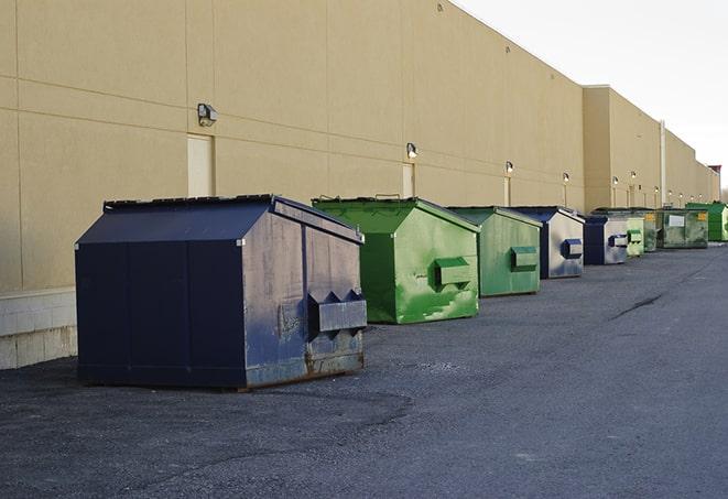 a construction worker unloading debris into a blue dumpster in Miller MO